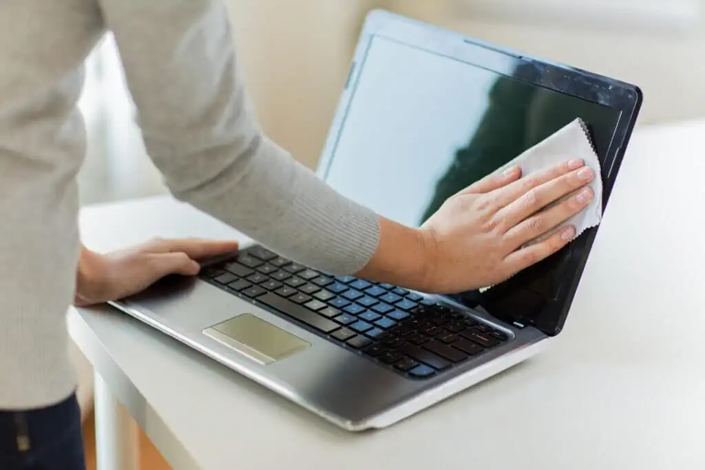 primo piano delle mani della donna che puliscono lo schermo del laptop