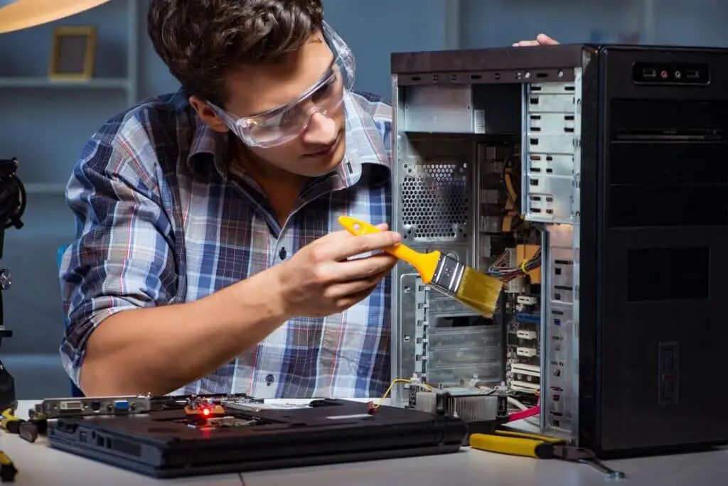 Hombre de reparación de computadoras limpiando el polvo con cepillo